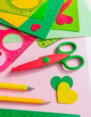 Children's workplace for making crafts. Cutting multi-colored hearts from foamiran. Children's stationery: scissors, ruler, pencils and marker.