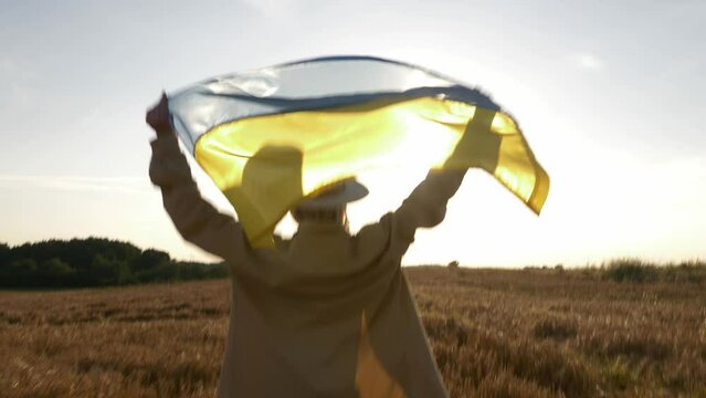 Stylish White Woman In Hat With Ukrainian Flag Running In Yellow Wheat Field