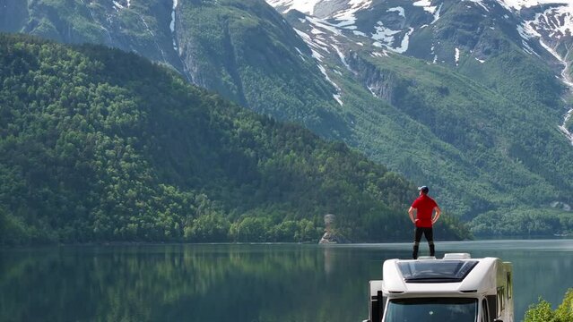 Caucasian Tourist Enjoying Scenic Norwegian Landscape While Staying on a Roof of His RV
