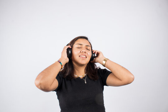 picture of latin woman singing and listening to music with wireless headphones. Concept of people and hobbies.