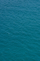 Aerial view of aquamarine sea surface. Rough sea texture. Top view natural background of rippled sea-green sea water. Marine theme with copy space.