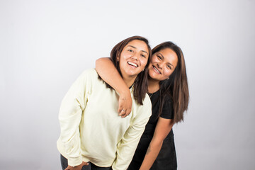 Fototapeta premium Portrait of two young women embracing on a white studio background. Concept of people.