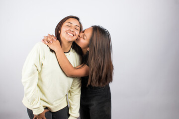 Portrait of two young women embracing on a white studio background. Concept of people.