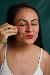 Fototapeta premium latin woman applying ice to her skin as rejuvenating anti-aging treatment, anti-aging concept