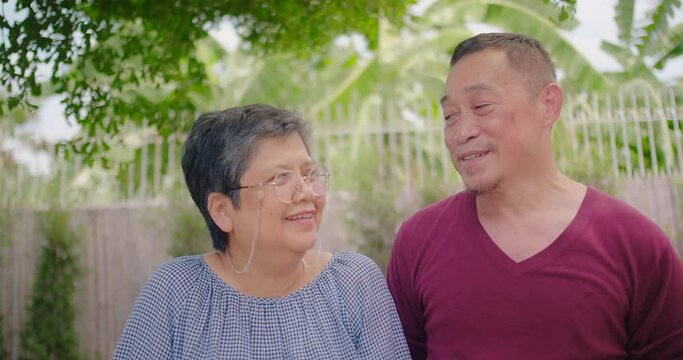Happy loving couple Asian family elderly husband and wife talking smiling and laugh together in the park, Retirement senior couple relax and enjoy romantic outdoor lifestyle vacation together.