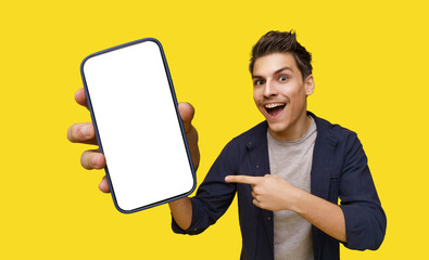Smiling young man depicted holding big smartphone in hand, inviting viewer to take closer look....