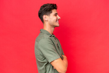 Fototapeta premium Young caucasian handsome man isolated on red background in lateral position