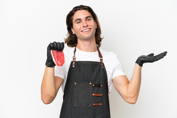 Butcher handsome man wearing an apron and serving fresh cut meat isolated on white background extending hands to the side for inviting to come