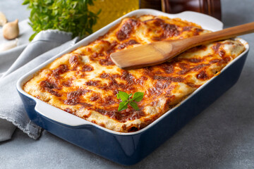 Portion of ground beef lasagna topped with melted cheese and garnished with fresh parsley served on...