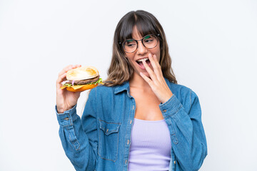 Young caucasian woman holding a burger isolated on white background with surprise and shocked facial expression