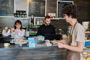 Coffee shop workers, a young guy in an apron in focus