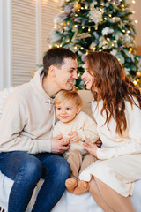 happy family. mom, dad and son on the couch by the Christmas tree.