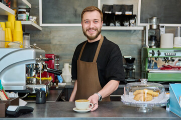 Portrait of barista male in an apron with freshly prepared cappuccino coffee