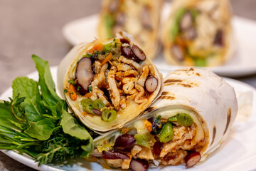 Chicken meat, French fries, vegetables and salad are wrapped in pita bread on a brown background.