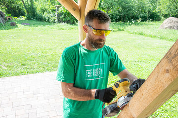Worker grinds the wood of angular grinding machine at his workstation