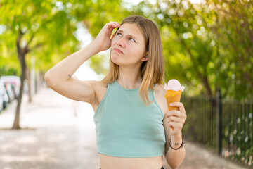 Young blonde pretty woman with a cornet ice cream at outdoors having doubts and with confuse face...