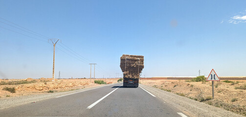 An overloaded truck driving through an arid Moroccan landscape