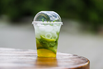 A plastic stand with a cool mojito drink (ice, mint, sparkling water, lime) in the afternoon