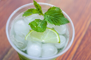 A plastic stand with a cool mojito drink (ice, mint, sparkling water, lime) in the afternoon