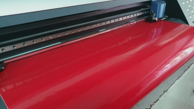 Cutting plotter. Plotter cuts red vinyl slowly, Cutting machine stickers. 