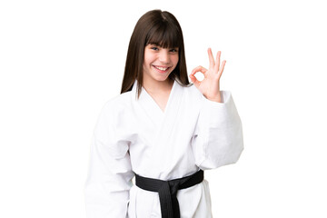 Little Caucasian girl doing karate over isolated background showing ok sign with fingers © luismolinero