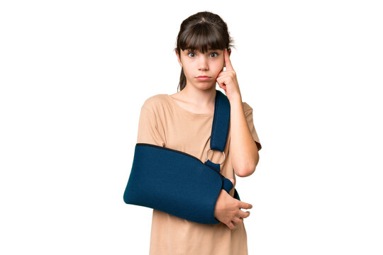 Little caucasian girl with broken arm and wearing a sling over isolated background thinking an idea
