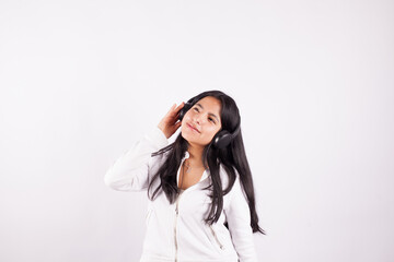 Fototapeta premium Photograph of young woman listening to music on a white studio background. Concept of music and hobbies.
