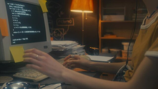 Young woman wearing headphones turing on music on personal cassette player while working on code, 90s aesthetics