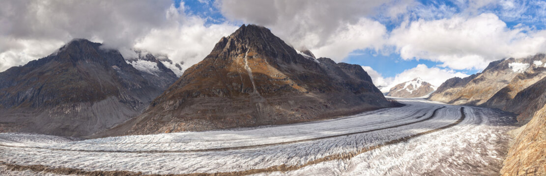 Panoramic photo of the Aletch Glacier in the Swiss Alps. Huge blocks of dirty ice against the backdrop of the mountains Olmenhorn and Gaeisshorn in Switzerland