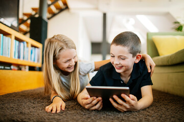 Young boy and girl using a digital tablet at home together