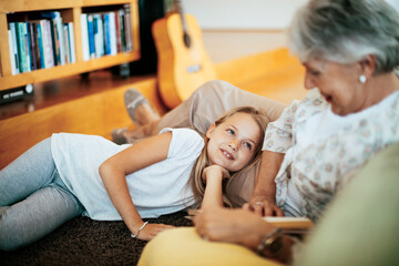Young girl spending time with her grandmother in the living room of their home