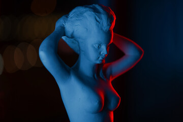 Naked woman's plaster sculpture, modern art. Art sculpture with red light on black background