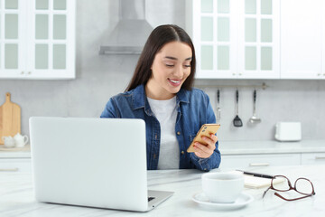 Home workplace. Woman with smartphone at marble desk in kitchen