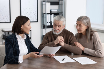 Elderly couple consulting insurance agent about pension plan at wooden table indoors - obrazy, fototapety, plakaty