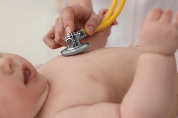 Fototapeta premium Pediatrician examining little baby with stethoscope in clinic, closeup