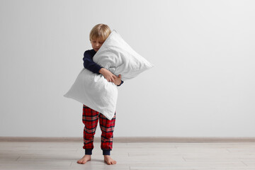 Little boy hugging pillow indoors, space for text