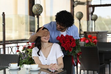 International dating. Handsome man presenting roses to his girlfriend in restaurant - Powered by Adobe