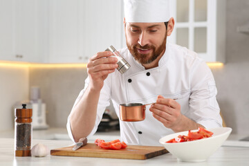 Professional chef adding salt into scoop at marble table in kitchen