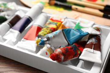 Pack of tubes with oil paints on wooden table, closeup