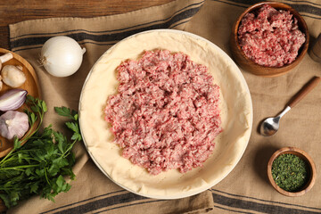 Flat lay composition with raw dough and ingredients on wooden table. Baking meat pie