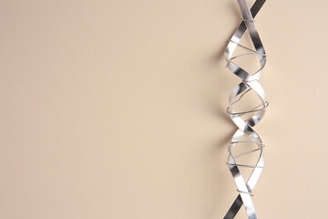 DNA molecular chain model made of metal on beige background, top view. Space for text