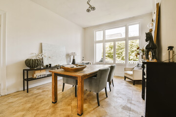 a dining room with a wooden table and grey chairs in front of a large window that looks out onto the street