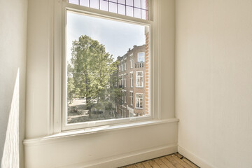 an empty room with a tree in the window and a view of a street outside area through the window pane