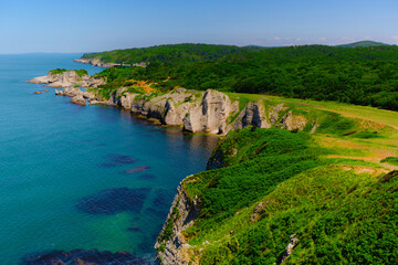 Fototapeta na wymiar White rocks with green grass by sea on summer sunny day