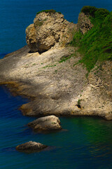 Green rocky island in sea closeup on summer sunny day.
