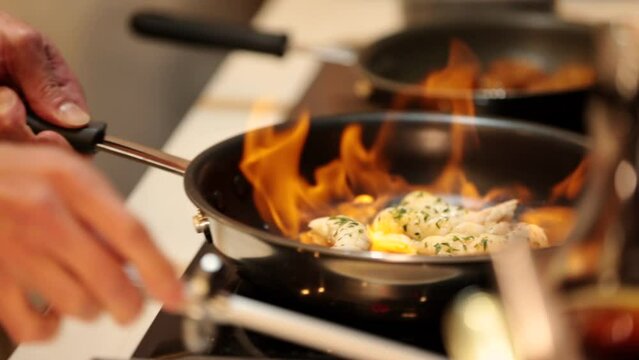 海老をフライパンでフランベし炎を上げる料理人