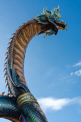 King of Naga, Phaya Si Mukda Maha Muni Nilapala Nakharat, Thai dragon or serpent king statue in Mukdahan temple with the blue sky background. - obrazy, fototapety, plakaty