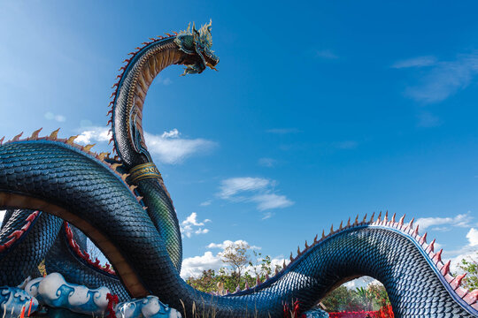 The majestic and greenish-blue colored Naga statue is 122 meters long and 20 meters high in Wat Roi Phra Phutthabat Phu Manorom, Mukdahan, Thailand, with a blue sky background