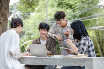Group of Asian college student reading books and tutoring special class for exam on grass field at outdoors. Happiness and Education learning concept. Back to school concept. Teen and people theme.