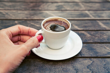 Beautiful female hand with a manicure holding a cup of strong espresso coffee. High quality photo
